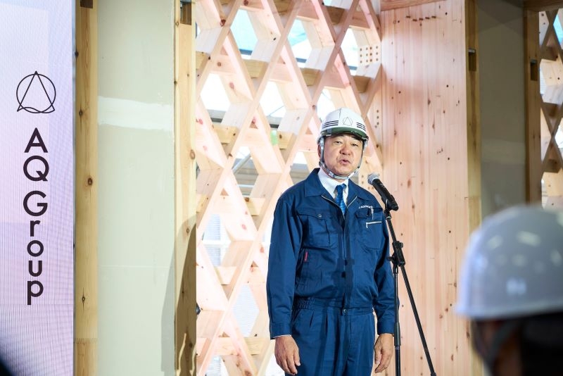 構造体でもあり意匠的でもある組子格子耐力壁の前で挨拶する代表取締役社長宮沢俊哉